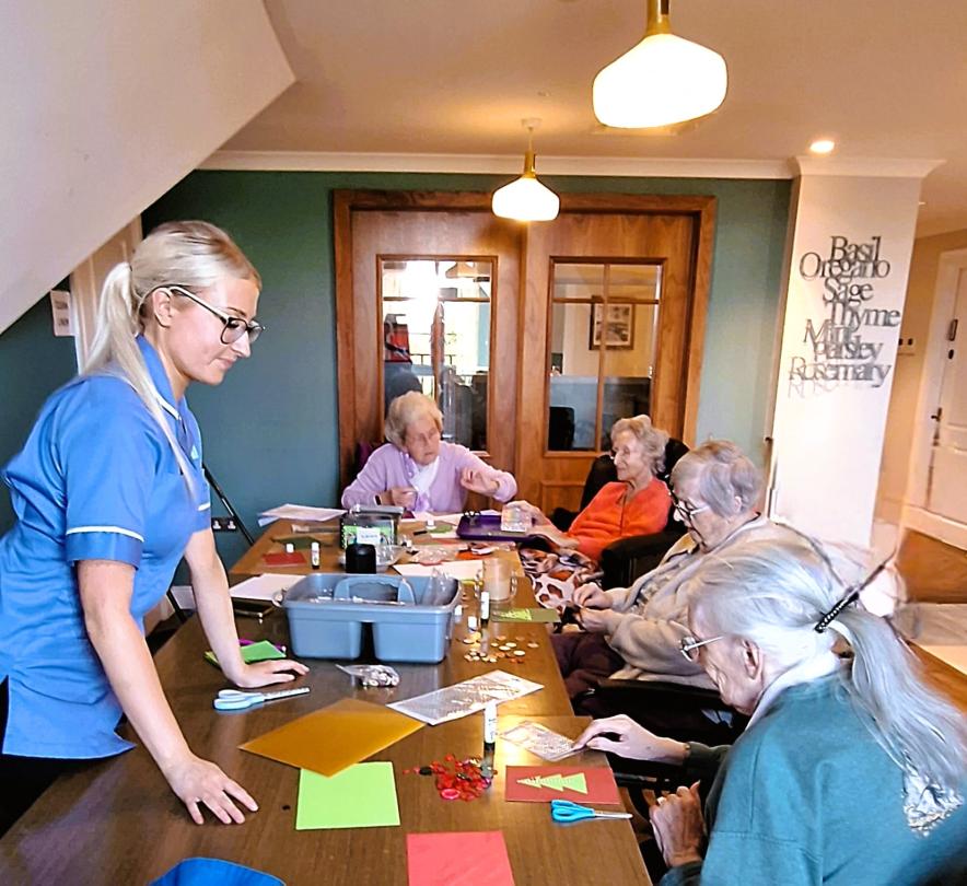 Residents making Christmas cards with button decorations for National Button Day