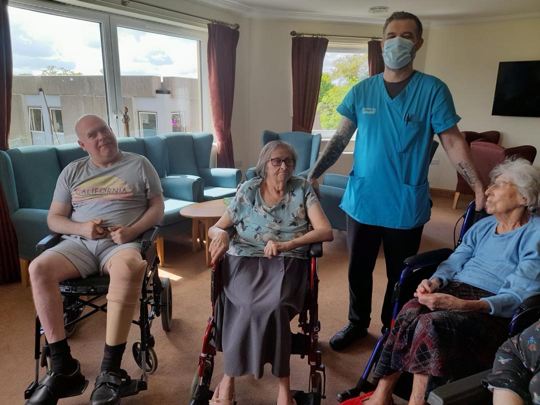 care home residents sat down ready for morning stretches with care staff in the middle