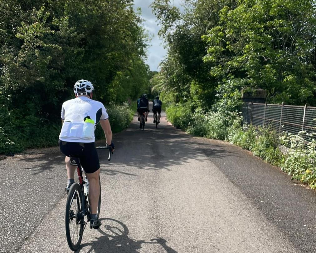 three cyclists in the middle of the road on a sunny day