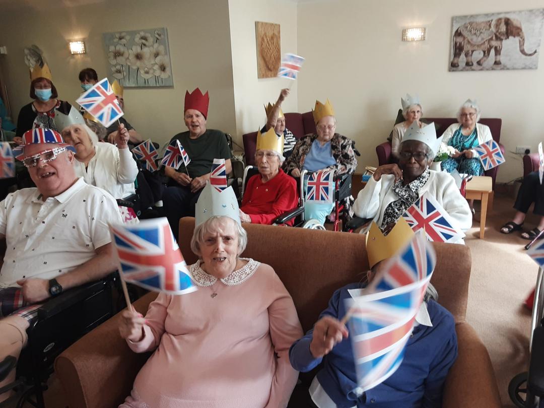 care home residents laughing and waving union jack flags