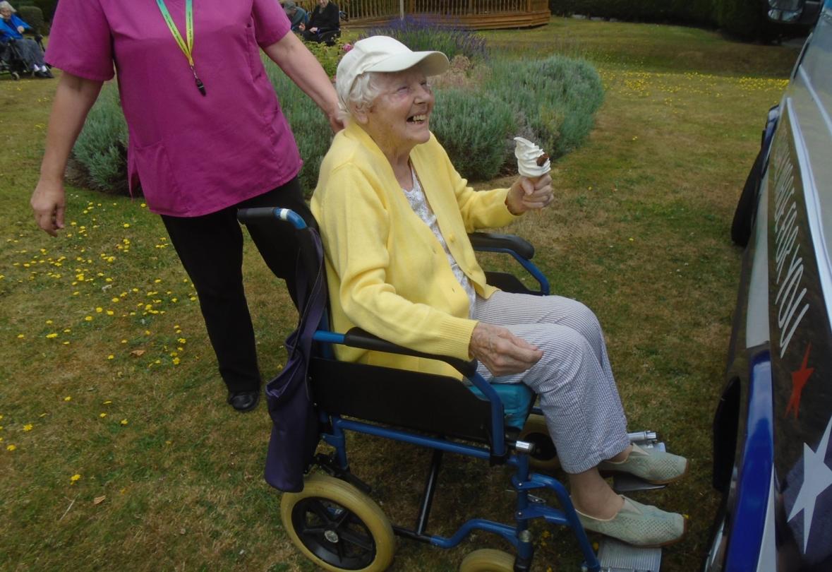 nursing home resident in wheelchair holding an ice cream cone smiling