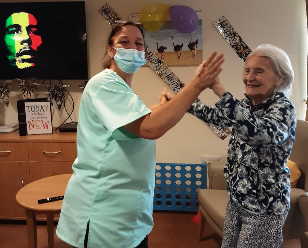 care home staff and resident dancing and smiling