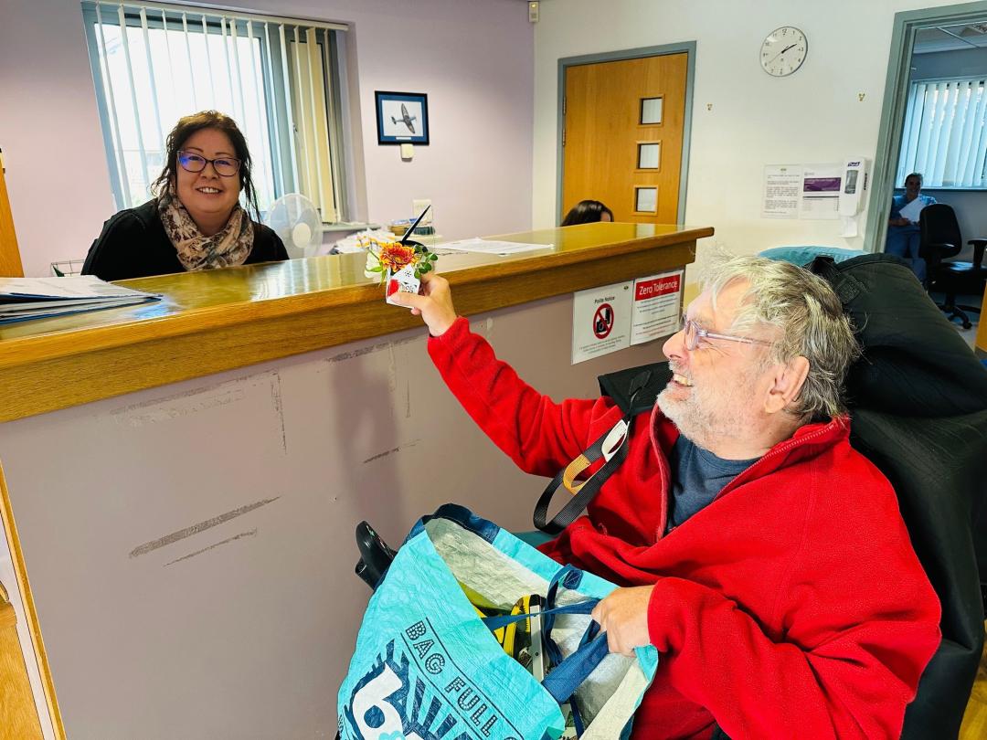 Johnny giving a flower box to a receptionist at Mendip Vale GP.