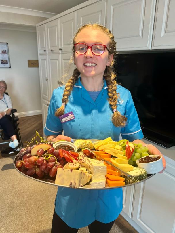 Olivia bringing a selection of cheeses for residents to enjoy