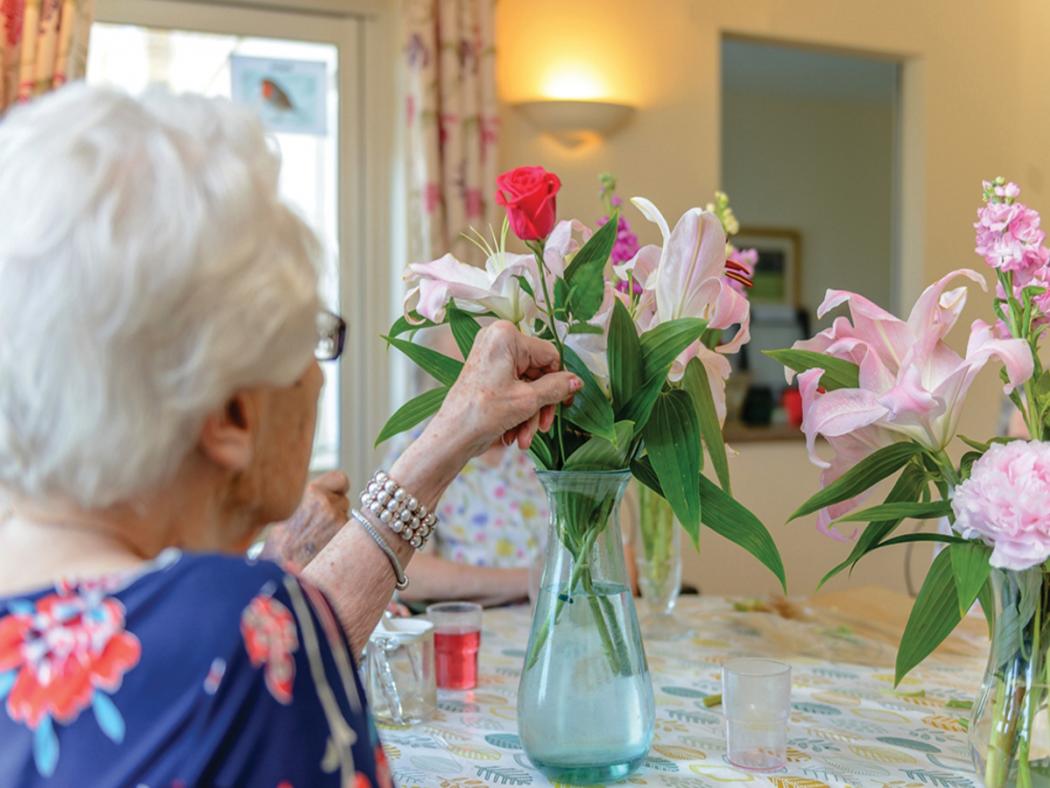elderly woman arrange flowers in a vase