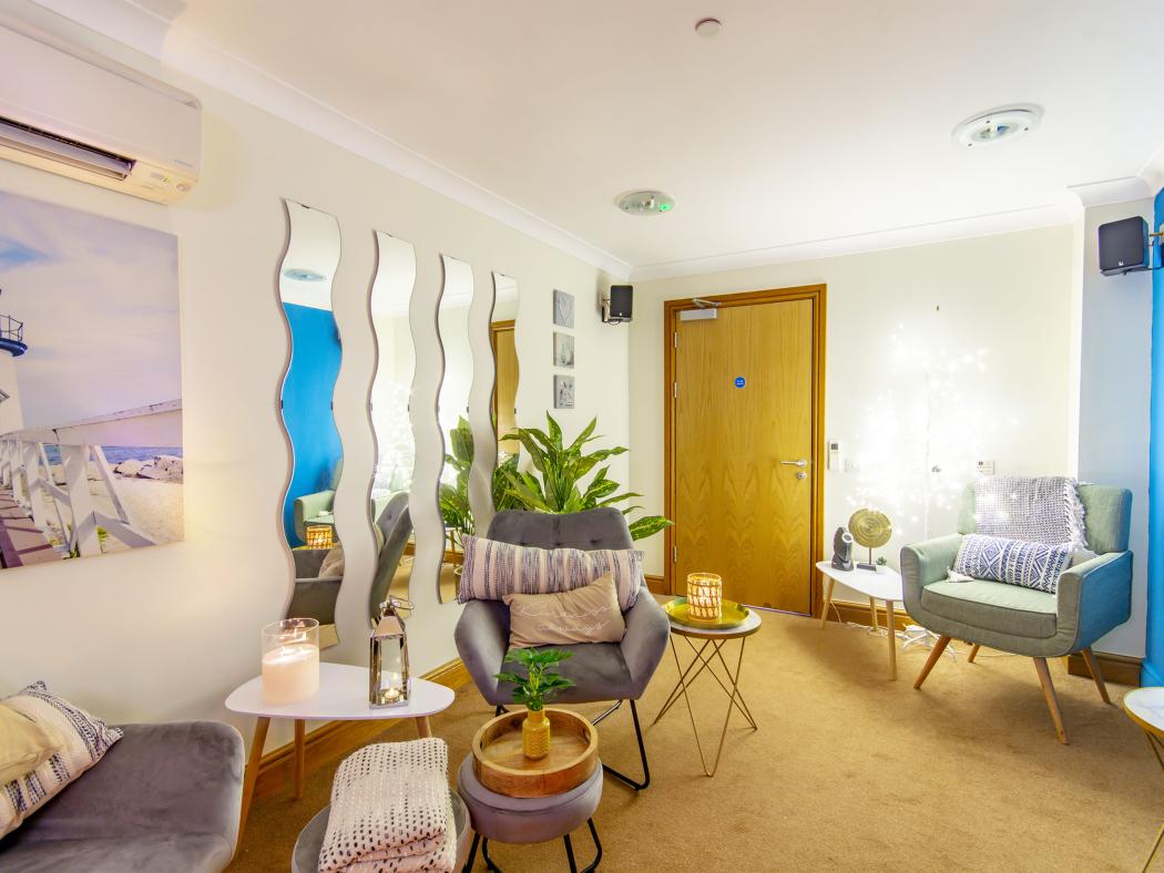 A serene relaxation room featuring wave-shaped mirrors, soft furnishings, and ambient lighting, designed for comfort and tranquility