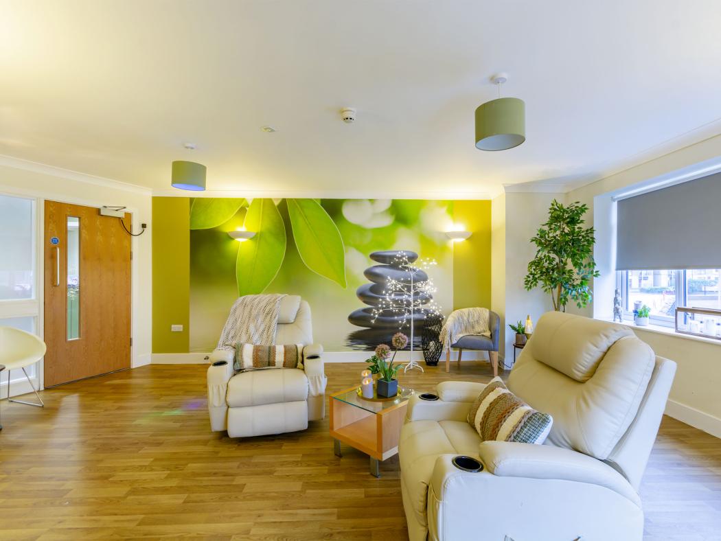 Relaxation room at Olive Tree House with comfortable recliner seating and a calming nature-themed mural