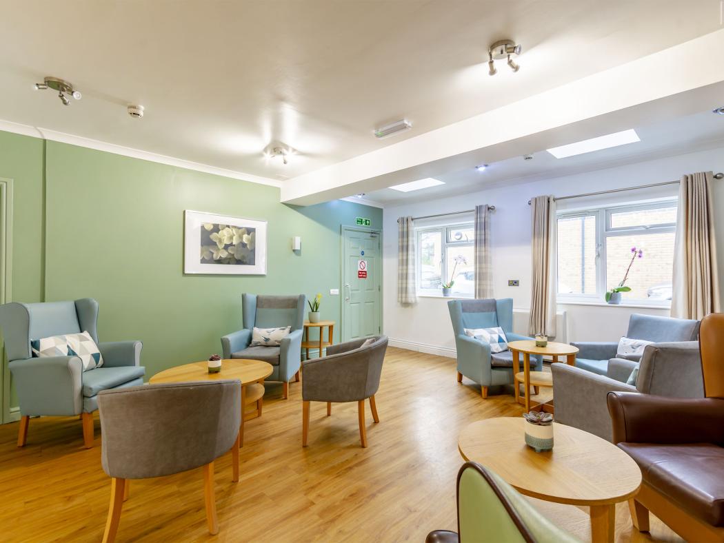 Relaxing communal area at The Grove Residential Home, decorated in shades of green with comfortable armchairs