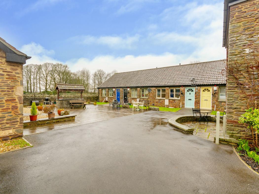Outdoor courtyard at The Grove Residential Home, featuring stone walls, garden seating, and a wishing well