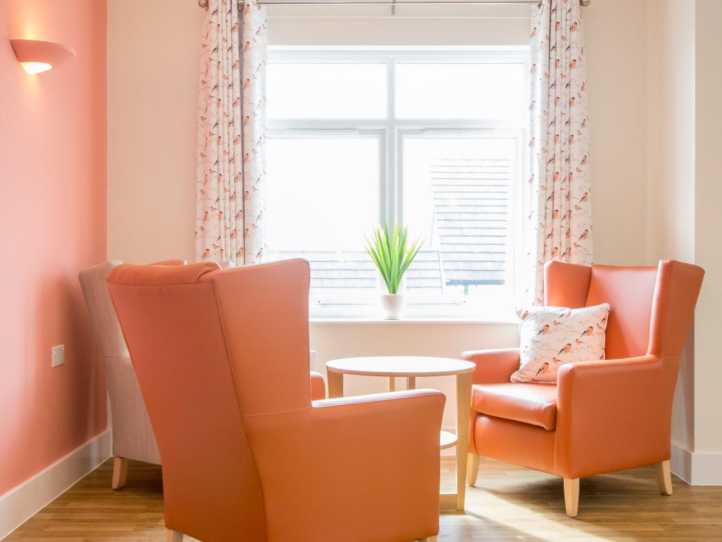 Bright and welcoming corner at Rose Garden Care Home, with armchairs and a wooden table next to a window