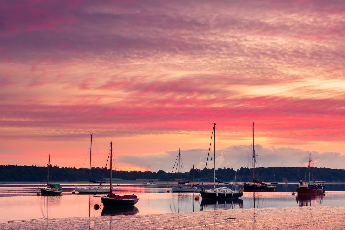 View of sunset on beach with boats 