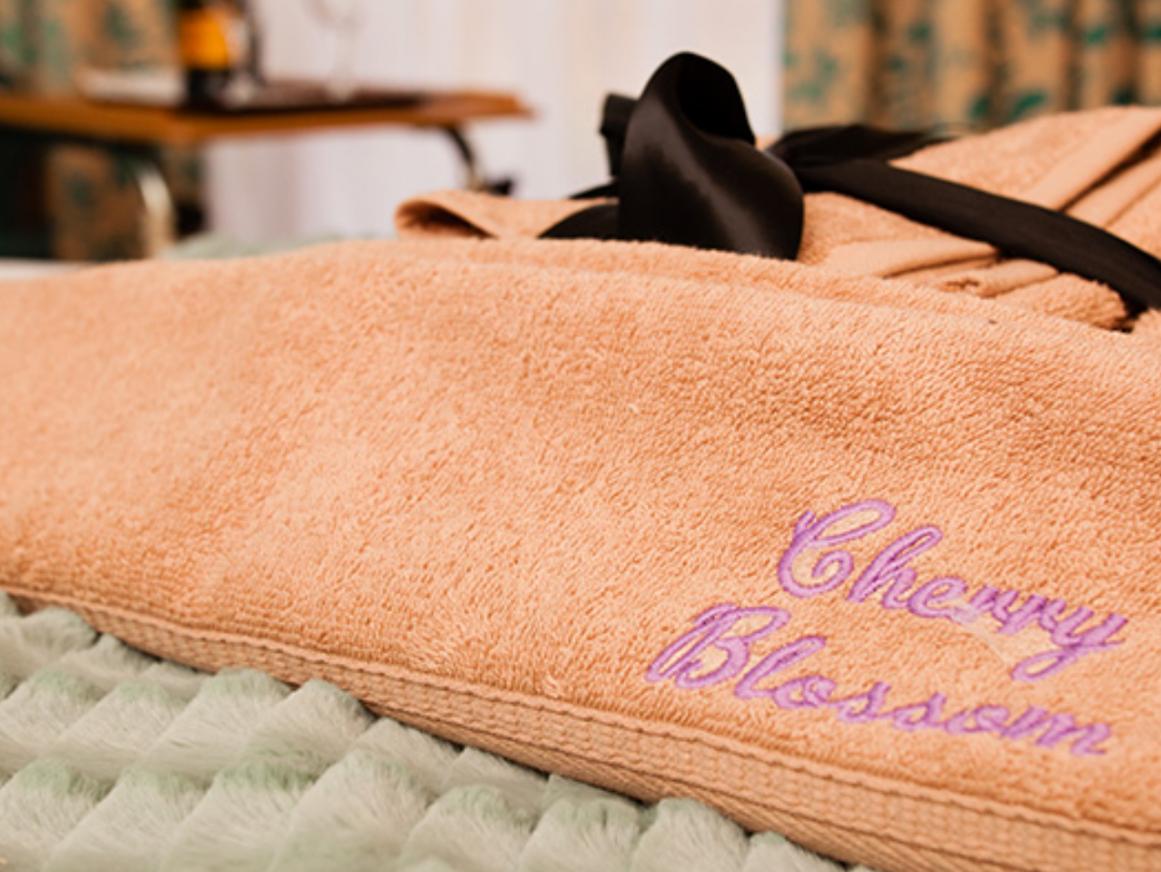 Folded orange towel with 'Cherry Blossom' embroidered in pink 
