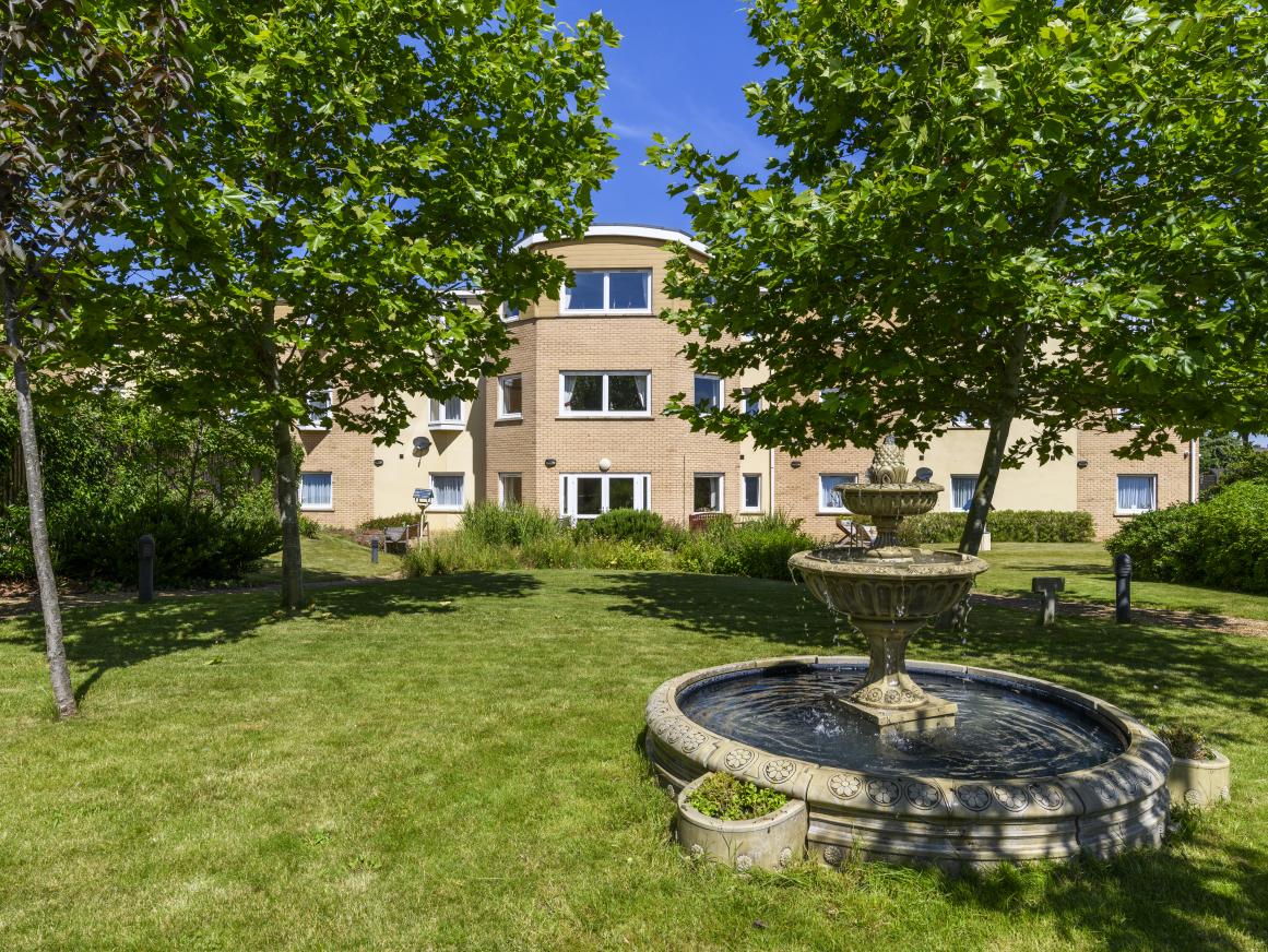 exterior image of Cherry Blossom Care Home garden, building and fountain on a sunny day