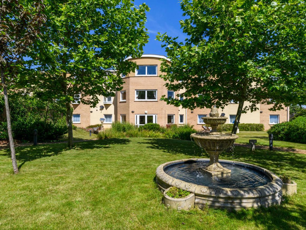 exterior image of Cherry Blossom Care Home garden, building and fountain on a sunny day