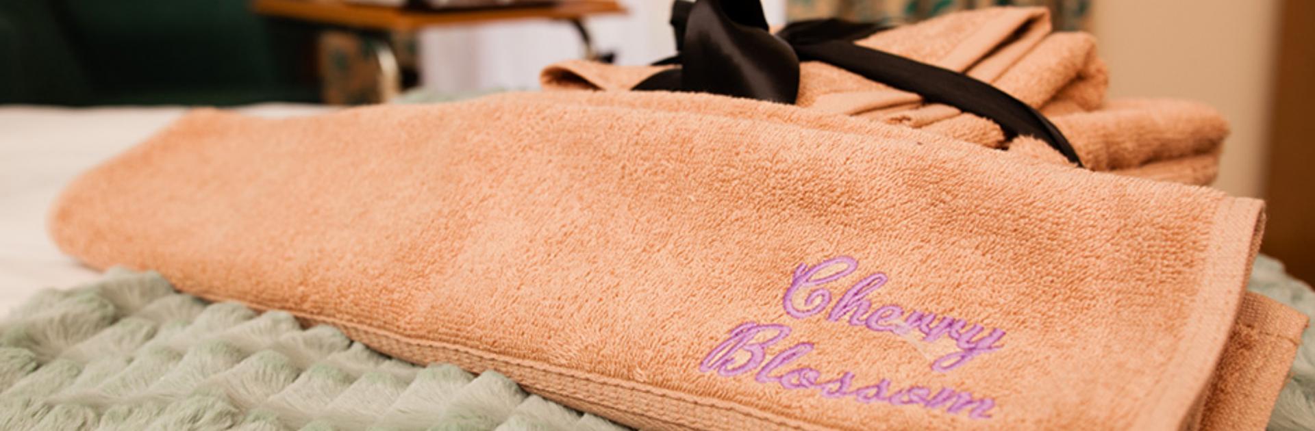 Folded orange towel with pink embroidered writing that reads 'Cherry Blossom'