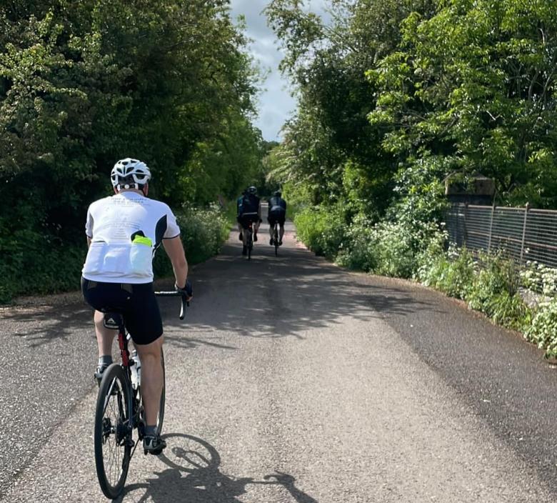 three cyclists in the middle of the road on a sunny day