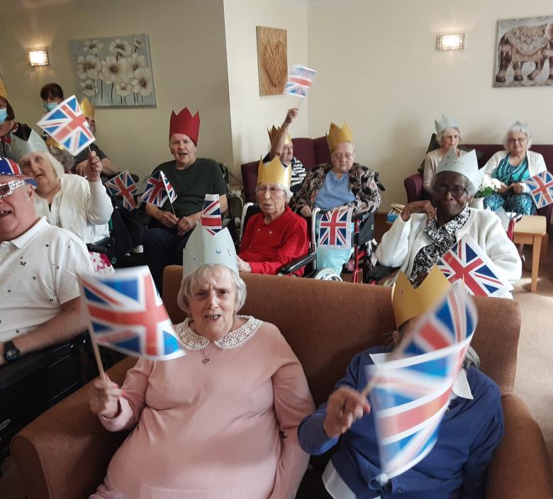 care home residents laughing and waving union jack flags