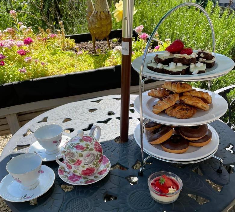 sweet treats on a table with cups and saucers for tea