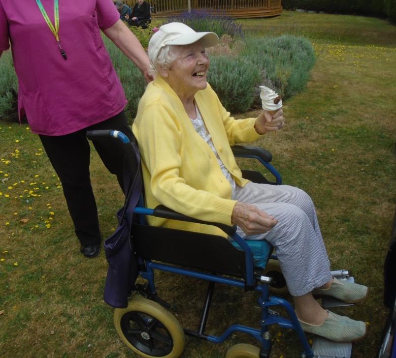 nursing home resident in wheelchair holding an ice cream cone smiling