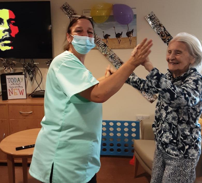 care home staff and resident dancing and smiling
