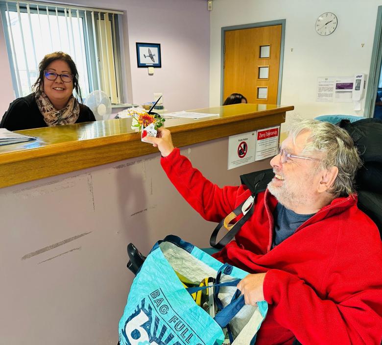 Johnny giving a flower box to a receptionist at Mendip Vale GP.
