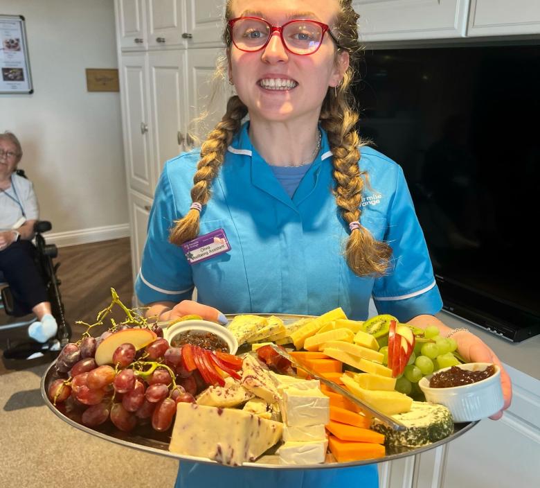 Olivia bringing a selection of cheeses for residents to enjoy
